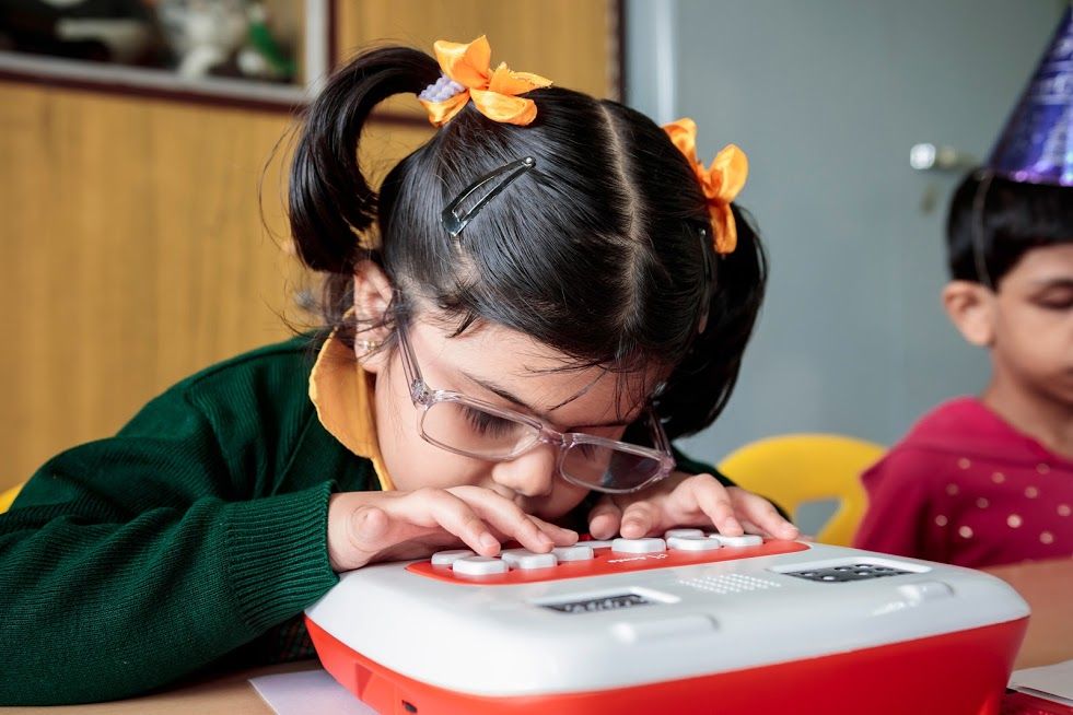 A young student uses her Annie, leaning in close