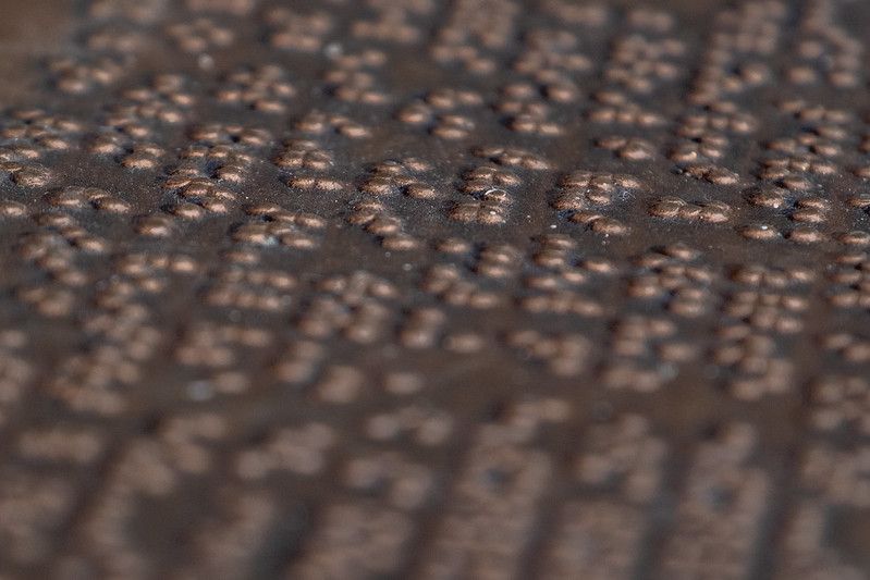 An embossed metallic sheet of Braille text is on focus