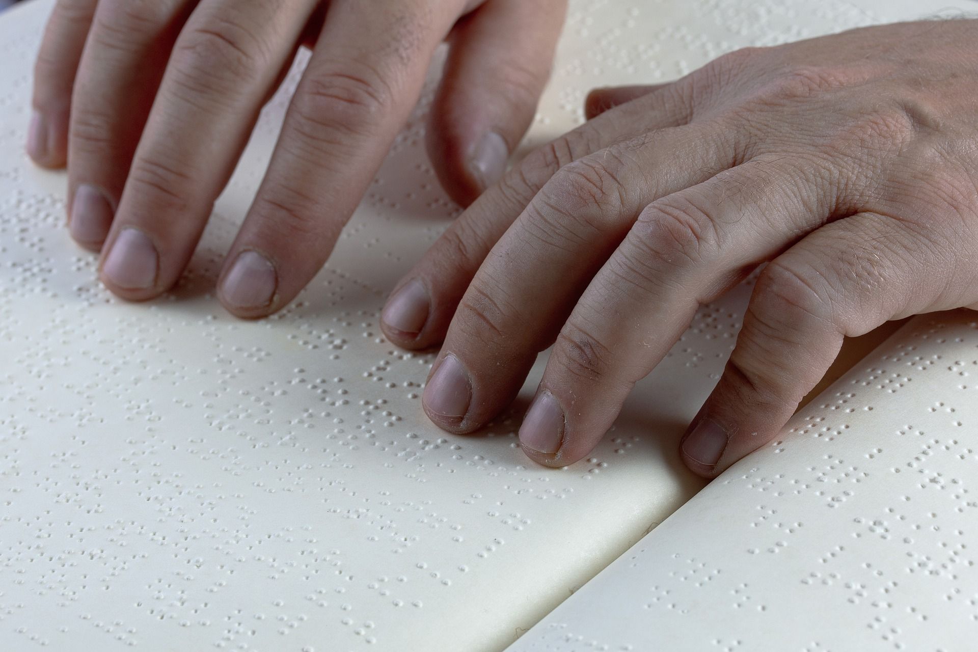 A person has their fingers placed on a page of Braille text to read