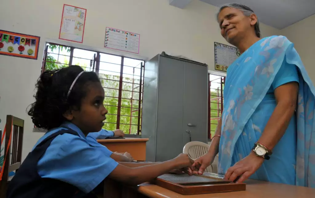 A teacher helps a student learn Braille