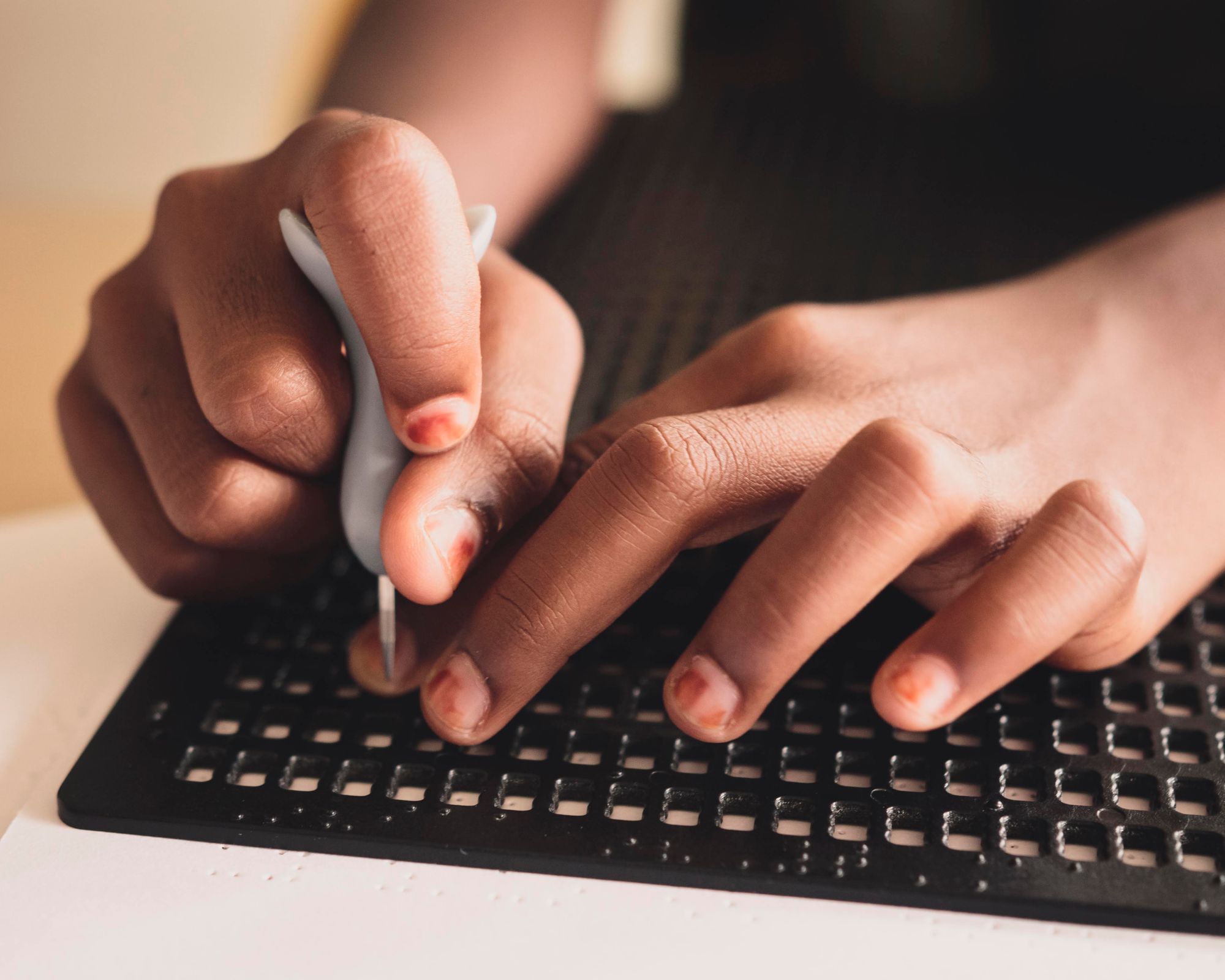 A person is using a Braille slate and stylus