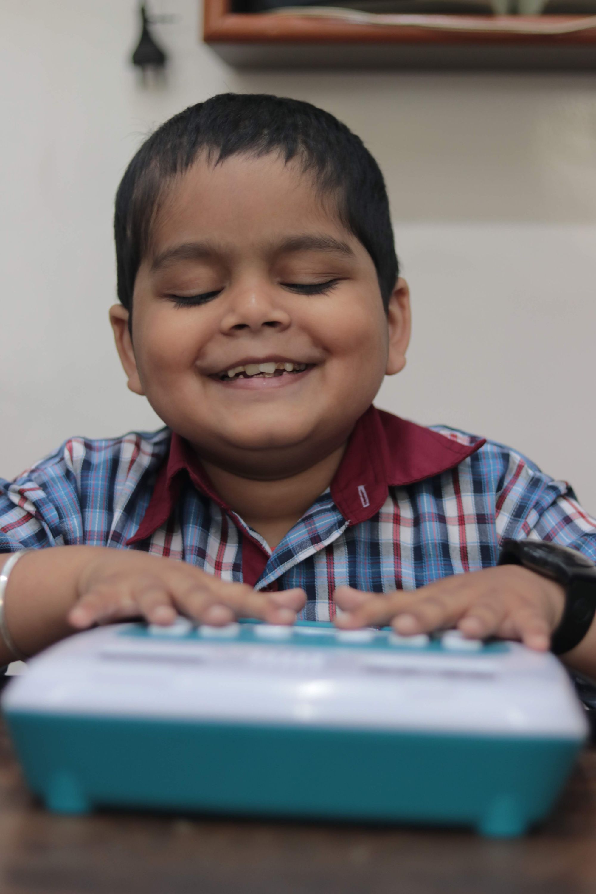 A smiling child in white, blue and red checked uniform plays on his Annie