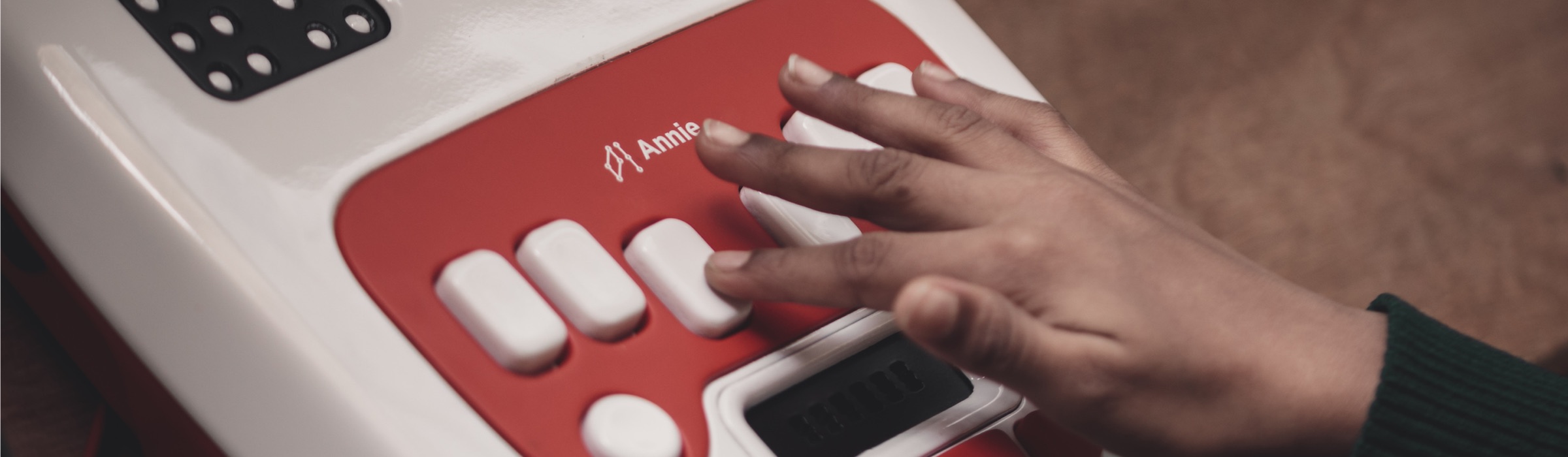 A learner’s hand resting on the keys of a red Annie